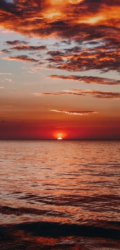 Serene sunset over the ocean with a vibrant orange sky.