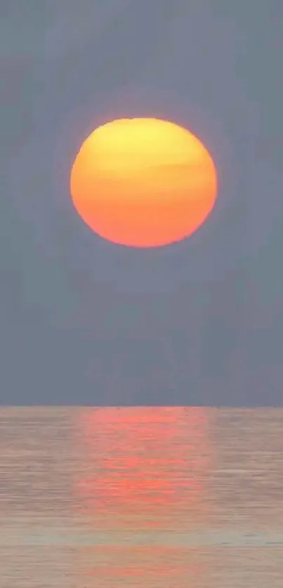 Sunset over ocean with warm colors and reflection on water, creating tranquility.