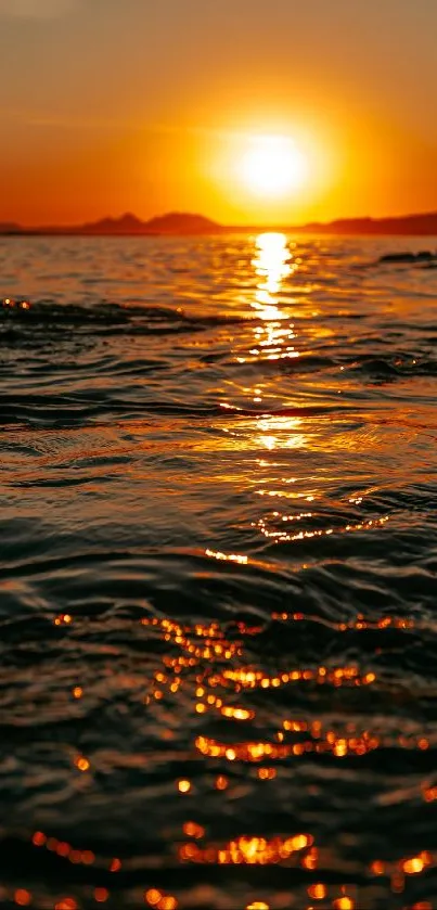 Orange sunset over ocean waves with serene reflections.