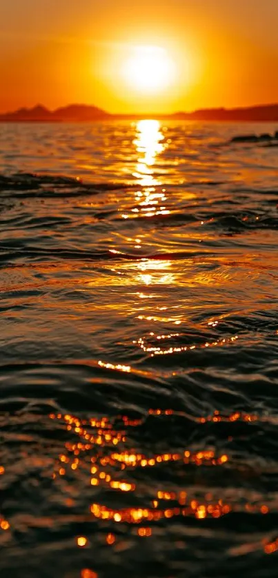 Vibrant sunset over ocean waves reflecting warm hues.