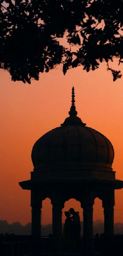 Silhouette of pavilion against orange sunset sky.