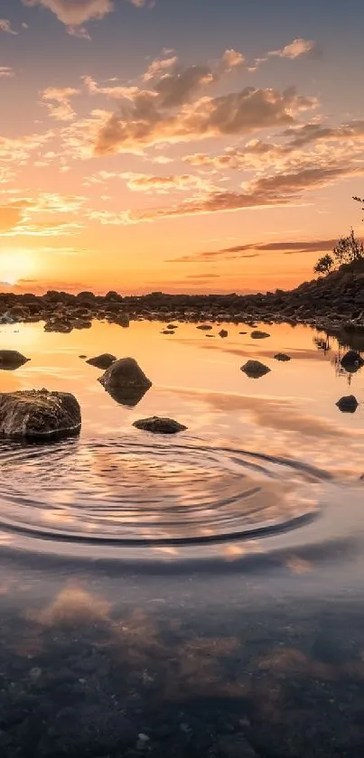 Serene sunset reflection on calm water with rocks and trees silhouetted.