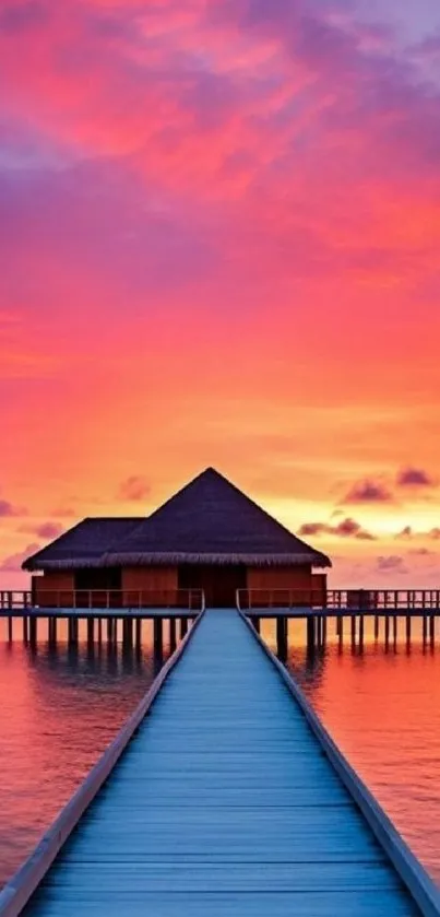 Overwater bungalow at sunset with vibrant sky and ocean view.