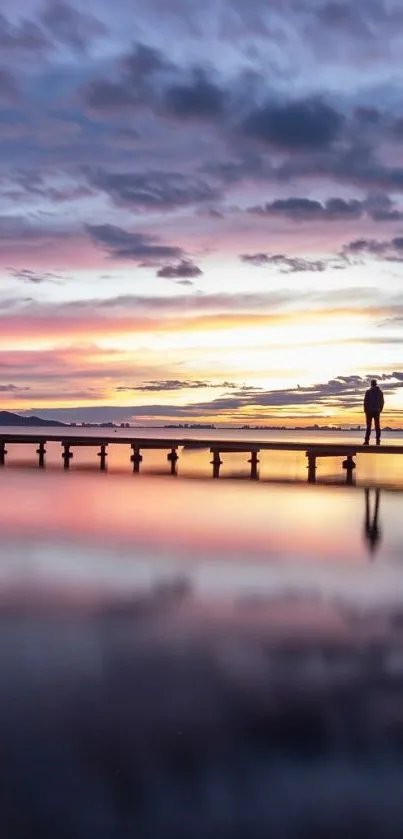 Silhouette on a pier at sunset over calm water.