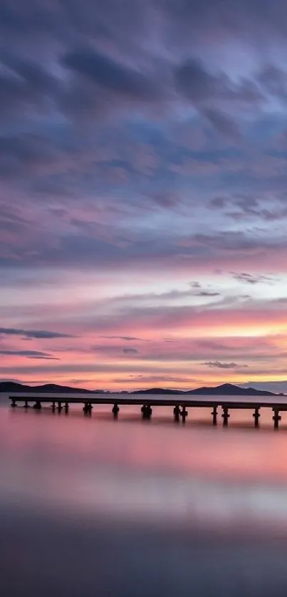 Calm sunset over pier with pink and purple sky reflections.