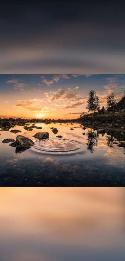 Serene sunset reflecting on calm water with colorful sky and rocky shoreline.