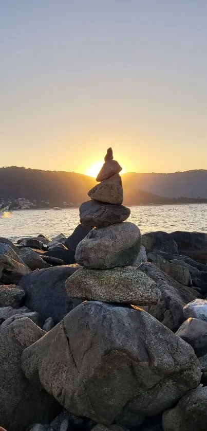 Stacked rocks with sunset over a tranquil shoreline.