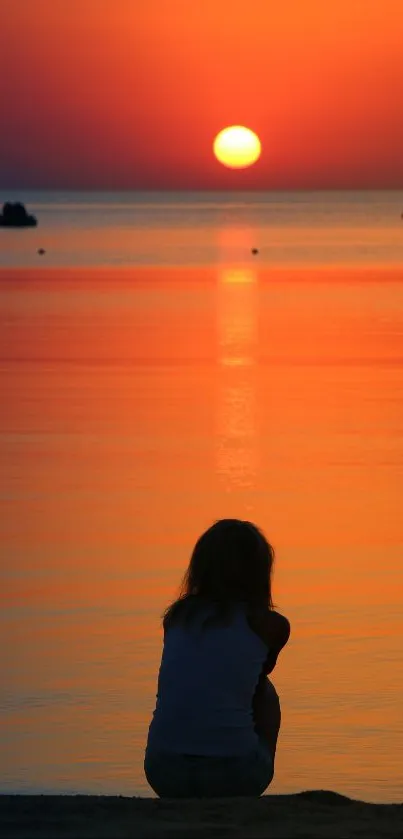 A silhouette against a vibrant orange sunset over a calm ocean scene.