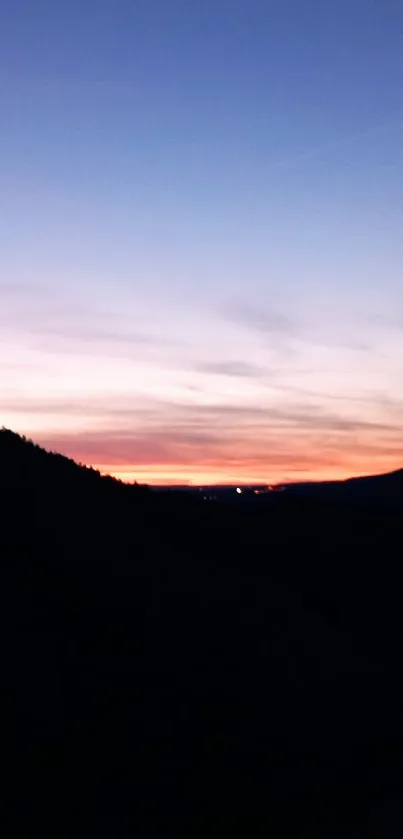 Serene silhouette sunset over mountains with vibrant colors.