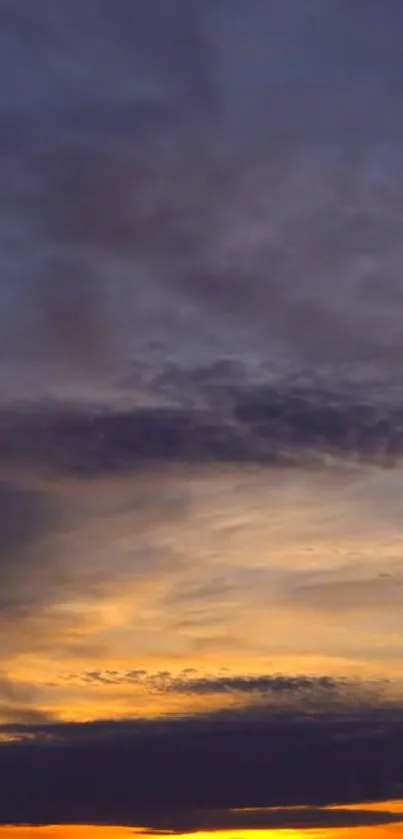 Serene sunset sky with clouds and orange hues.