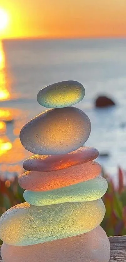 Balanced sea glass stones at sunset on the ocean shore.