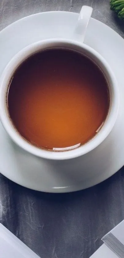 Serene tea cup on a marble table with leaves and pages.