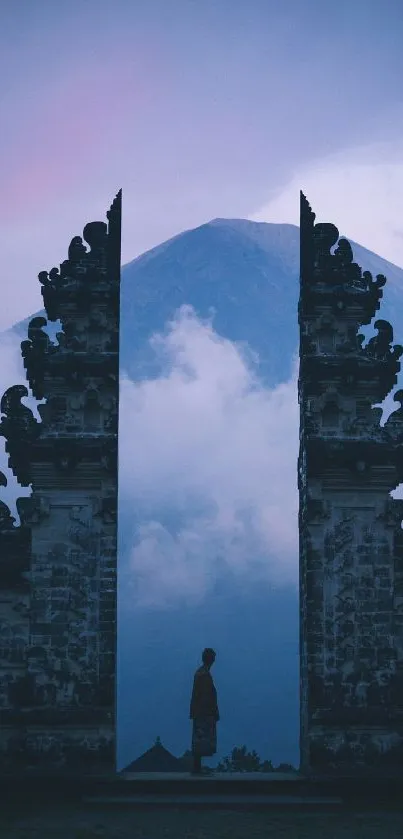 Silhouette at a temple gate against a misty mountain backdrop.