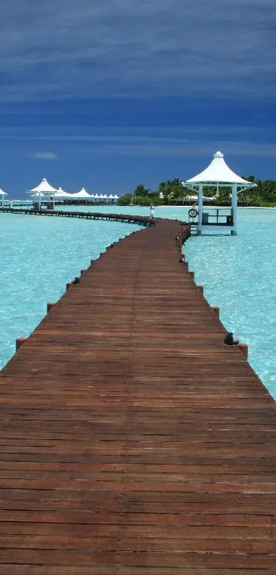Tropical pier extending into bright turquoise ocean under clear blue sky.
