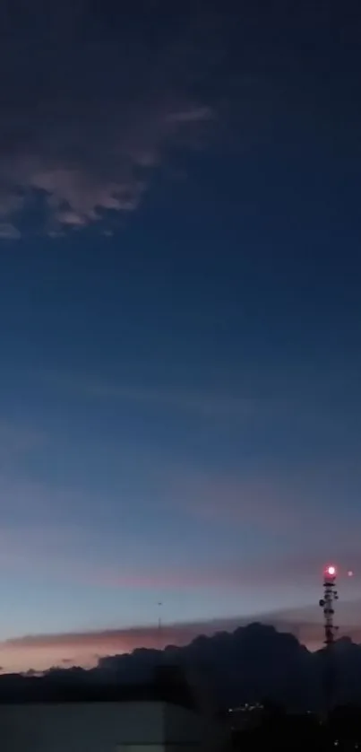 City skyline at twilight with a glowing tower and a dark blue sky.