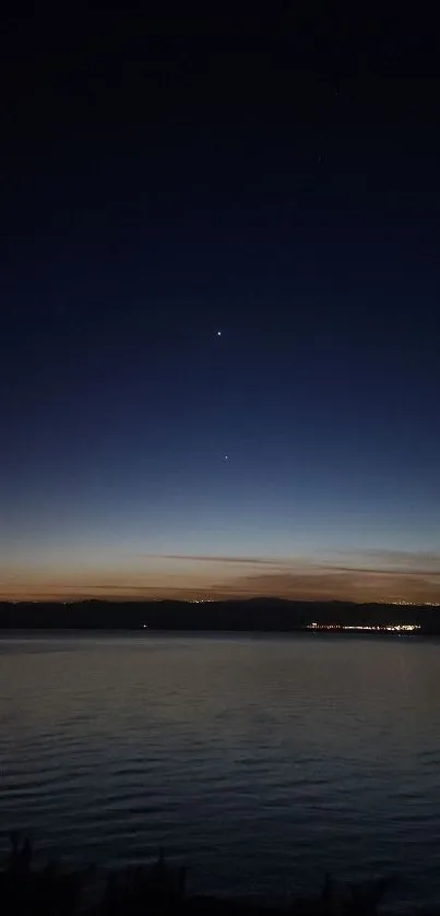 Serene twilight sky over calm water, with visible stars and a dark blue ambiance.