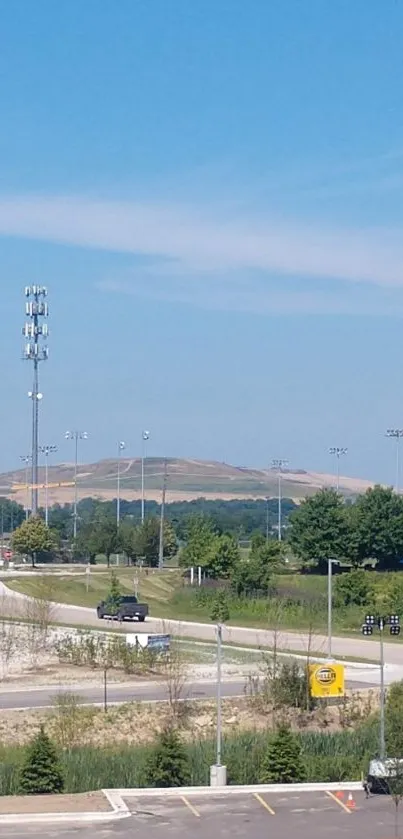 A serene view of a highway under a clear blue sky with surrounding greenery.