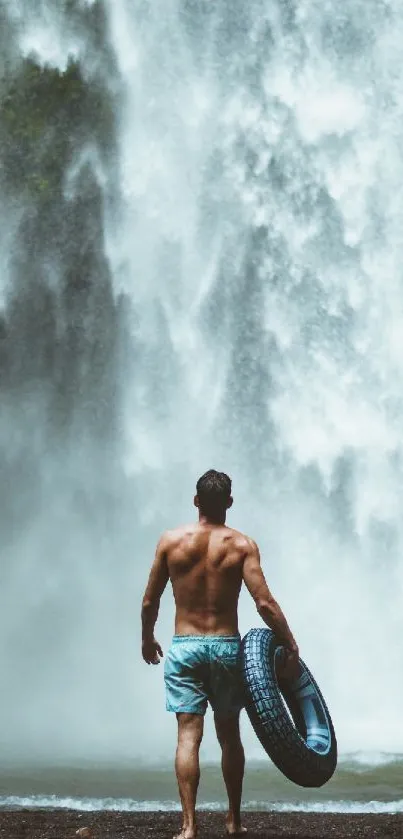Man standing by a majestic waterfall holding a tire tube.