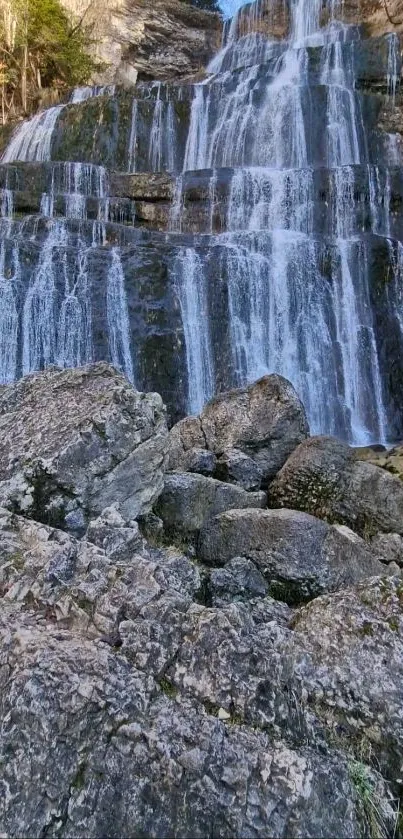 Cascading waterfall over rocky surfaces with gray stones.