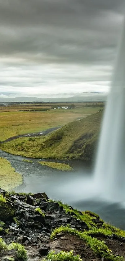 Beautiful waterfall in a lush, green landscape under a cloudy sky.