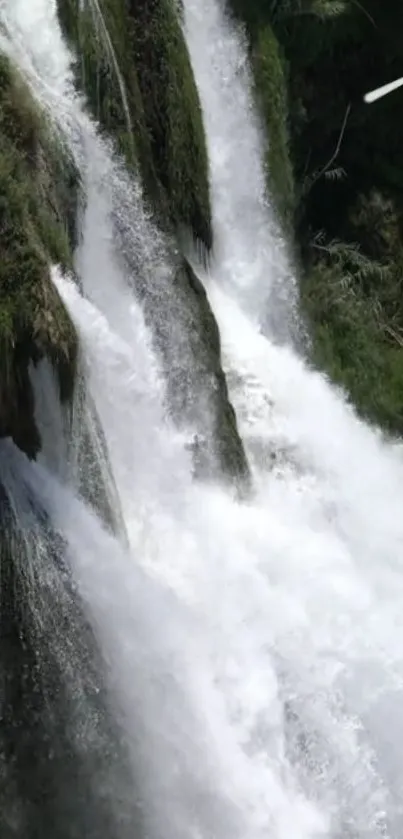 Breathtaking waterfall in a lush, green natural setting on a mobile wallpaper.