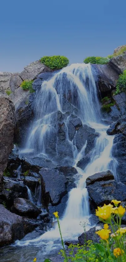 Cascading waterfall with blue sky and flowers in nature scene.