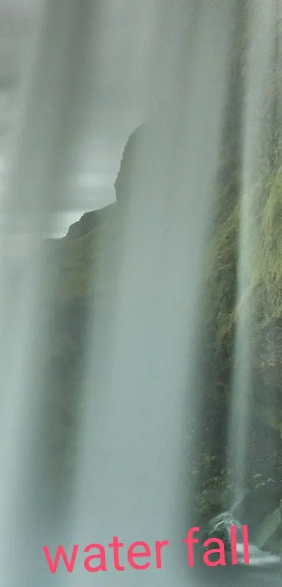 Tranquil waterfall cascading over rocks with green moss in background.