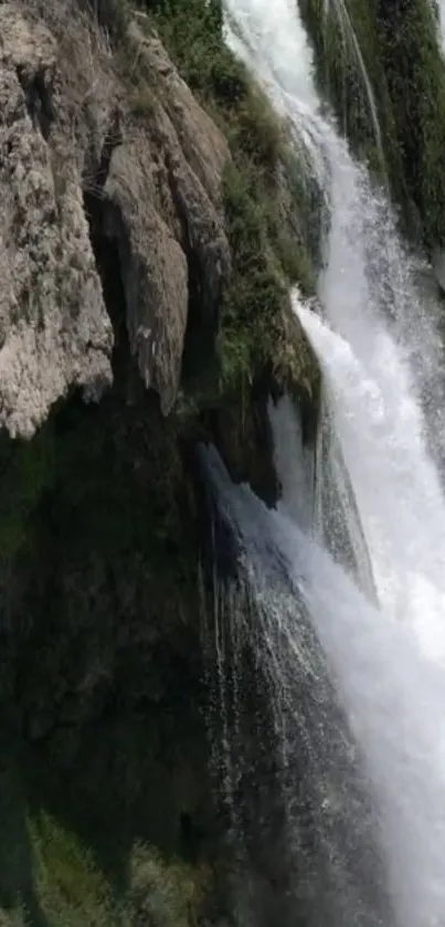 Stunning waterfall flowing over rugged rocks with lush greenery.