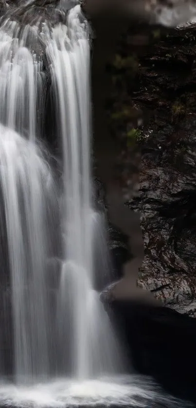 Serene waterfall cascading down rocky cliff in nature wallpaper.