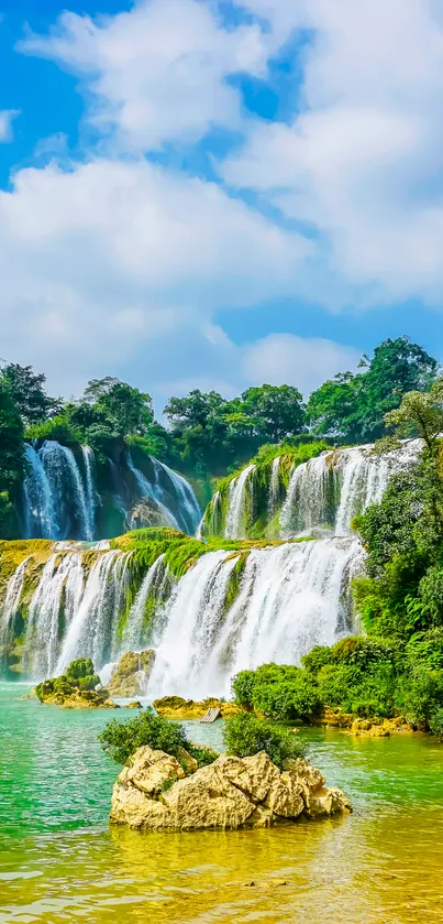 Serene waterfall with lush greenery under a bright blue sky.