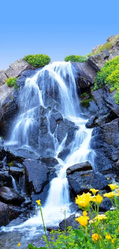 Serene waterfall with vibrant flowers and blue sky.