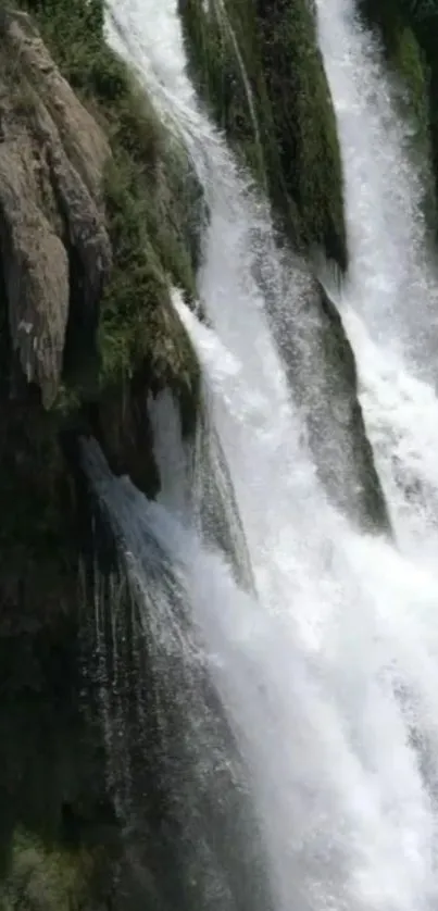 Serene waterfall cascading down rocky landscape with lush greenery.