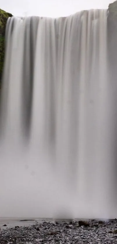 Cascading waterfall with gray mist and rocks in a serene natural setting.