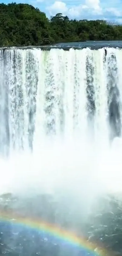 Majestic waterfall with a vibrant rainbow and clear blue skies.