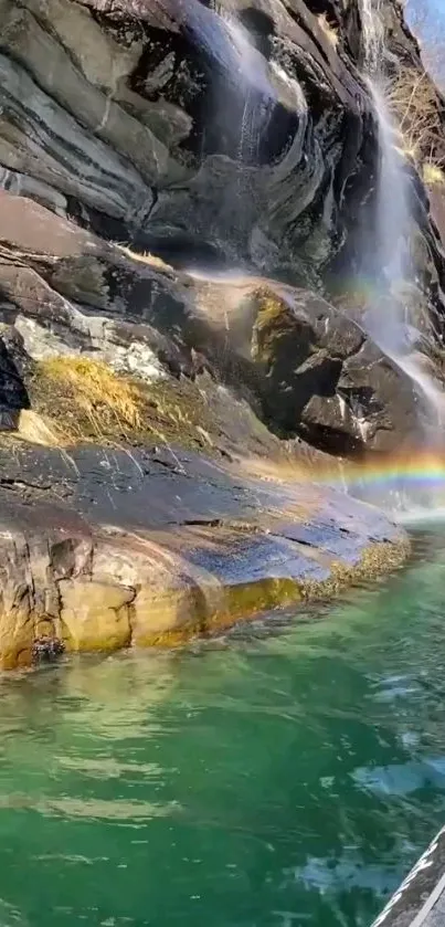 Waterfall with rainbow over serene green water.