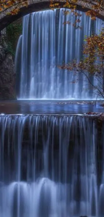 Serene waterfall flowing under a charming stone bridge.