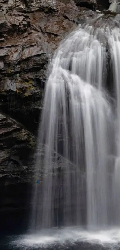 Serene waterfall with lush greenery on rocky cliffs.