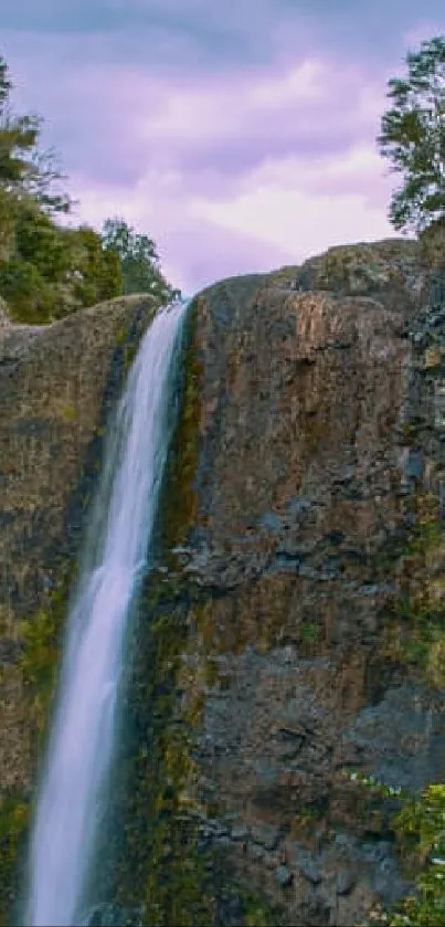 Serene waterfall amidst green cliffs and trees.