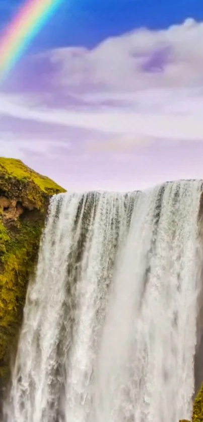 Majestic waterfall with a vibrant rainbow and blue sky.