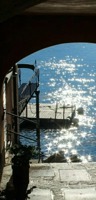 Sunlit pier through an archway with sparkling water.