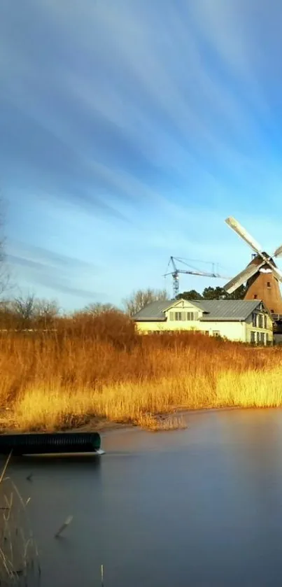 Serene windmill by river under a blue sky.