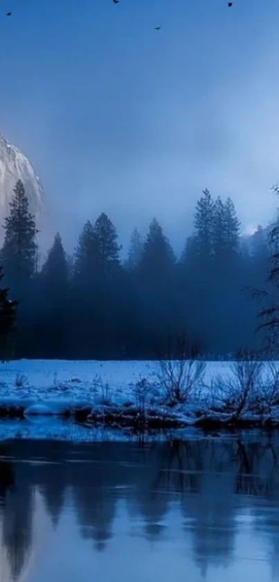 Snowy winter landscape with trees and lake under a blue sky.