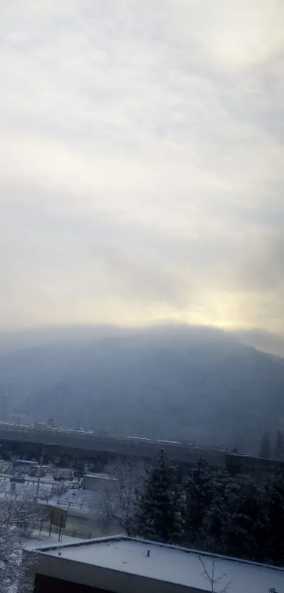 Serene snowy mountain view with misty gray skies and frosty trees.