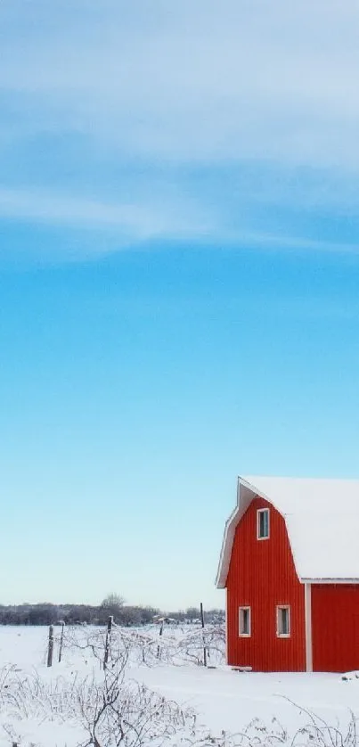 Red farmhouse in snowy landscape with clear blue sky.