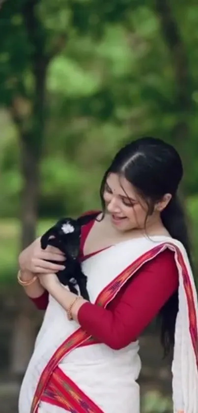 Woman holding a black goat with a lush green forest background.