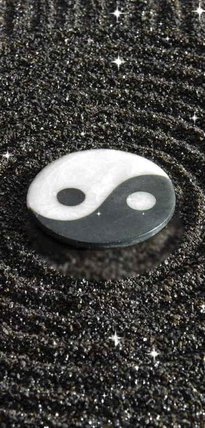 Yin Yang symbol on textured black sand with sparkling accents.