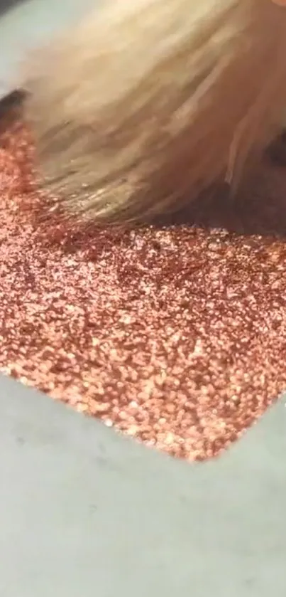 Close-up of a rose gold glitter texture with a makeup brush stroke.