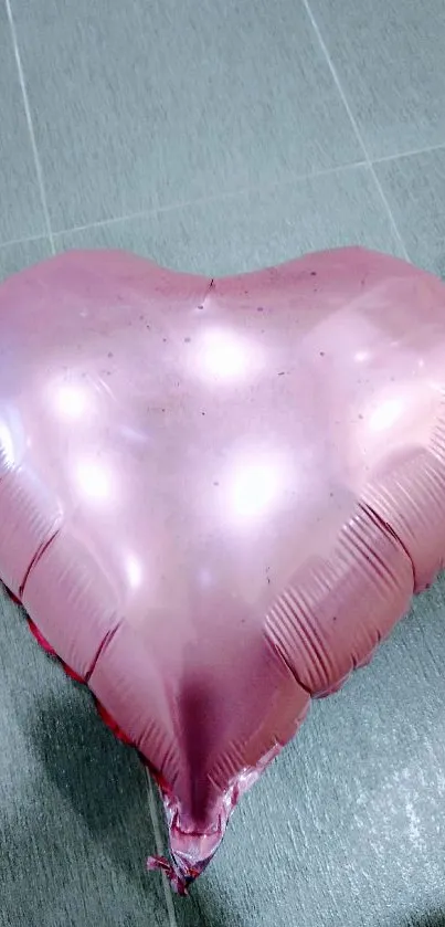 Pink heart-shaped balloon on a tiled floor, creating a romantic vibe.