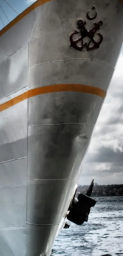 Gray ship under cloudy sky with ocean backdrop.