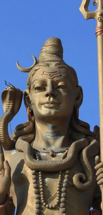 Bronze statue of Lord Shiva with a trishul against a blue sky.